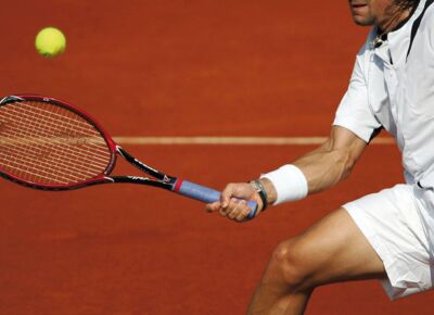 Detailaufnahme eines Tennisspielers, welcher zum Ball läuft, um diesen mit dem Tennisschläger zu treffen.