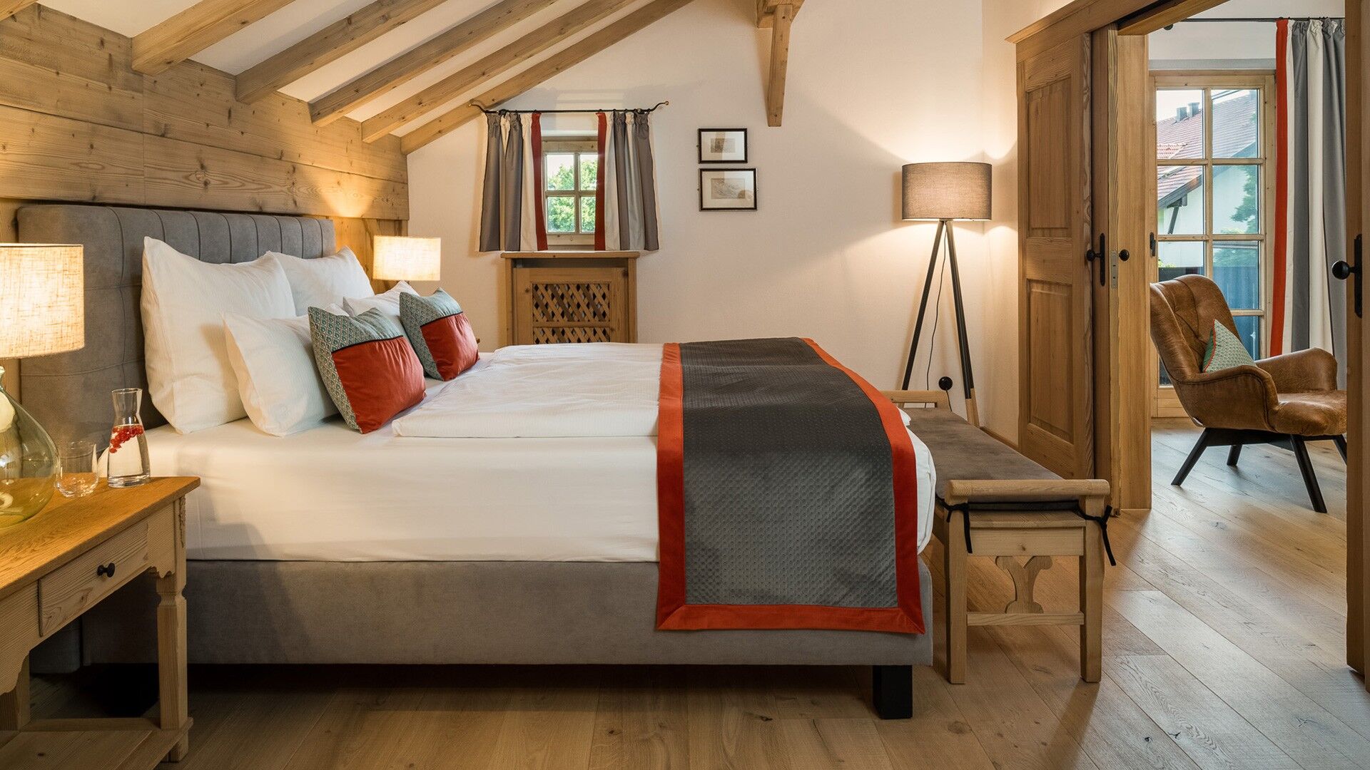 Ein großes Doppelbett stehend in einer aus Holzverkleideten Suite des Hotels Gut Ising am Chiemsee.