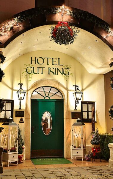 Eingangsbereich des Hotel Gut Ising am Chiemsee während der Weihnachtszeit mit großen Kerzen und Laternen vor der Eingangstür.