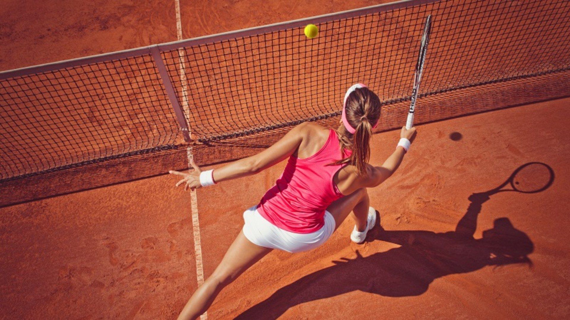 Tennisspielerin in Aktion während Sie einen Ball über das Netz schlägt im Hotel Gut Ising am Chiemsee.
